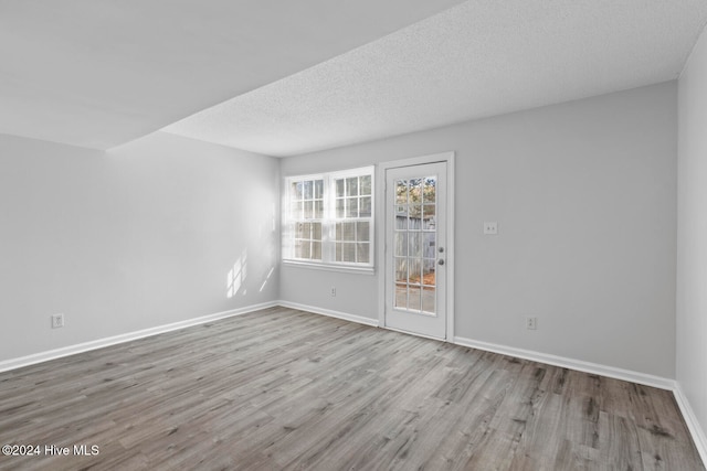 empty room featuring a textured ceiling and light hardwood / wood-style flooring