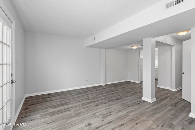 unfurnished room with hardwood / wood-style floors and a textured ceiling