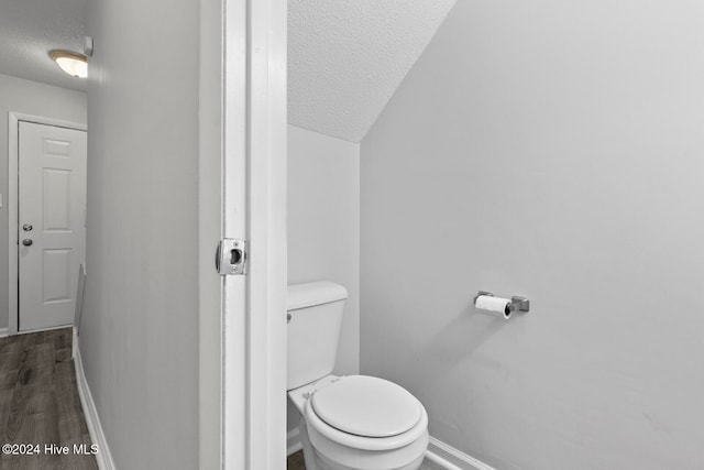 bathroom with wood-type flooring, a textured ceiling, toilet, and vaulted ceiling