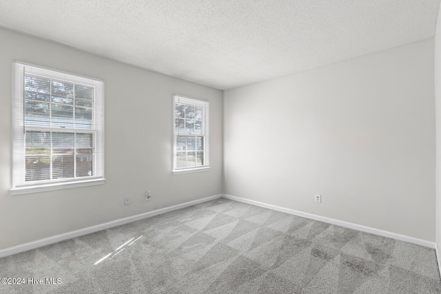 carpeted empty room featuring a textured ceiling