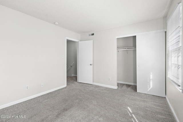 unfurnished bedroom with a closet and light carpet