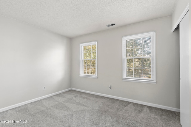 carpeted empty room with a textured ceiling