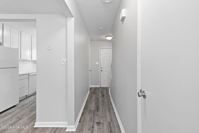 hallway featuring a textured ceiling and light hardwood / wood-style floors