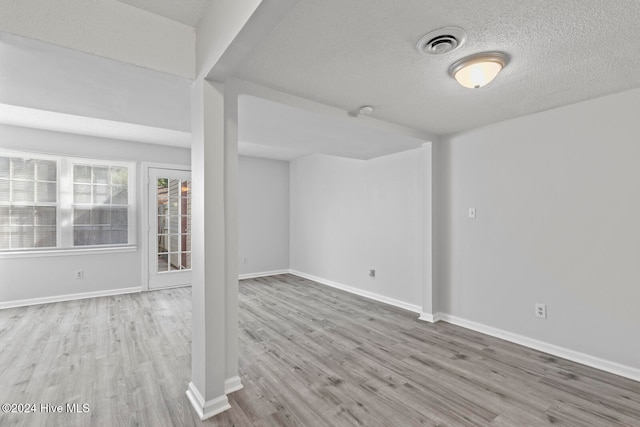 spare room featuring light wood-type flooring and a textured ceiling