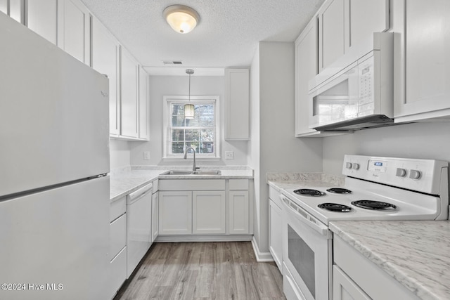 kitchen with light hardwood / wood-style floors, white cabinets, a textured ceiling, sink, and white appliances