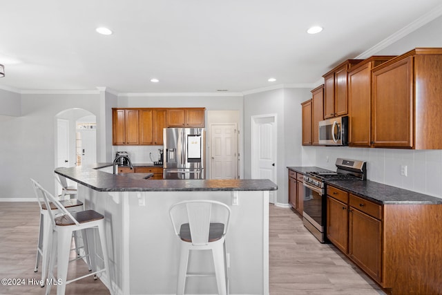 kitchen featuring a kitchen bar, light wood-type flooring, a kitchen island with sink, and appliances with stainless steel finishes