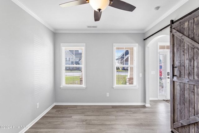 foyer featuring a barn door, light hardwood / wood-style flooring, and ornamental molding