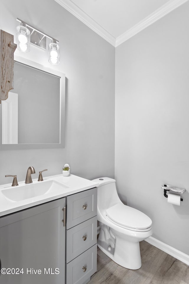 bathroom with wood-type flooring, vanity, toilet, and ornamental molding