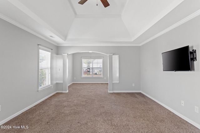 unfurnished living room featuring ornate columns, ceiling fan, a tray ceiling, carpet, and ornamental molding