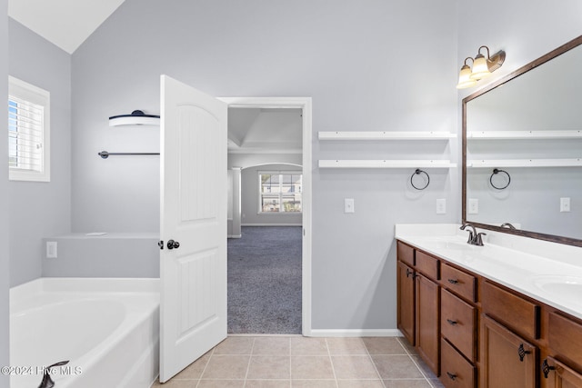 bathroom featuring tile patterned flooring, vanity, vaulted ceiling, and a wealth of natural light