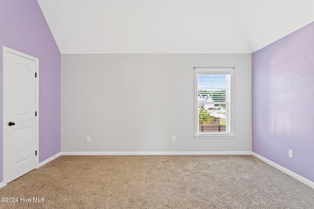 carpeted spare room featuring lofted ceiling