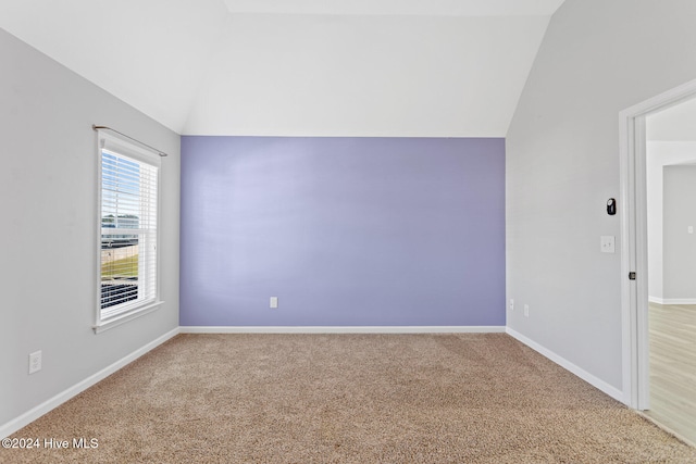 carpeted empty room with vaulted ceiling