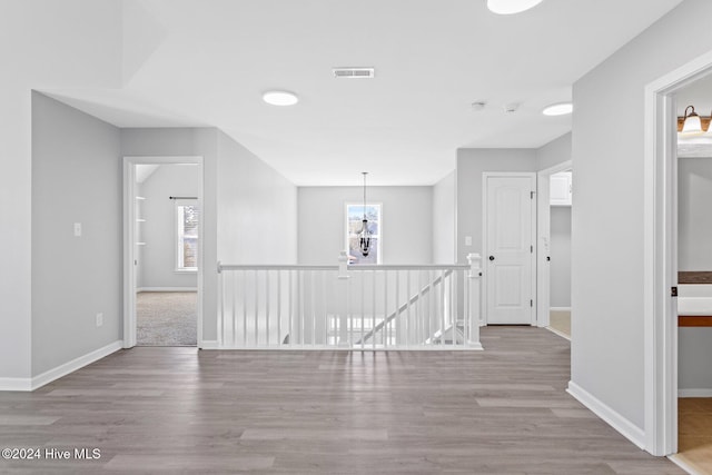 hall with an inviting chandelier and light hardwood / wood-style flooring