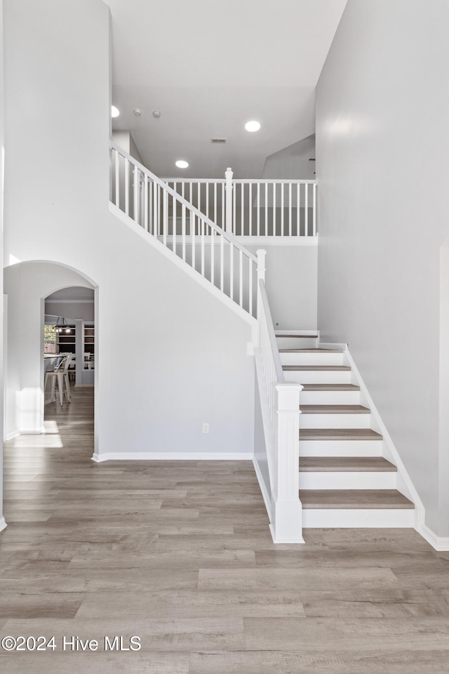 stairway featuring a towering ceiling and hardwood / wood-style flooring