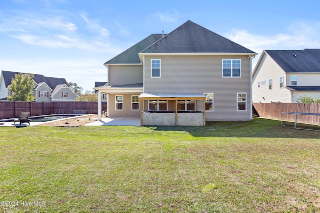 rear view of house with a lawn, a patio area, and a trampoline