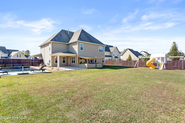 rear view of house featuring a lawn, a patio area, and a fenced in pool