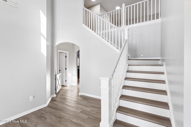 staircase featuring hardwood / wood-style floors and a high ceiling