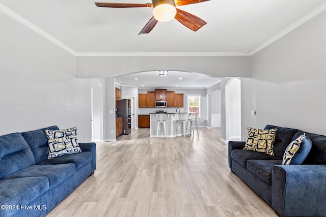 living room featuring ceiling fan, ornamental molding, and light hardwood / wood-style flooring