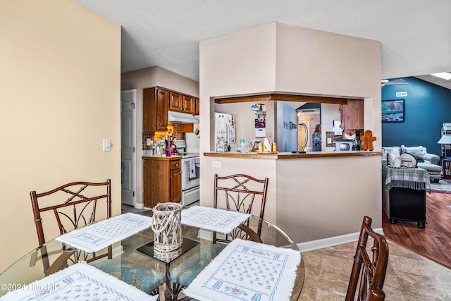 dining space featuring light wood-type flooring, a textured ceiling, and ceiling fan