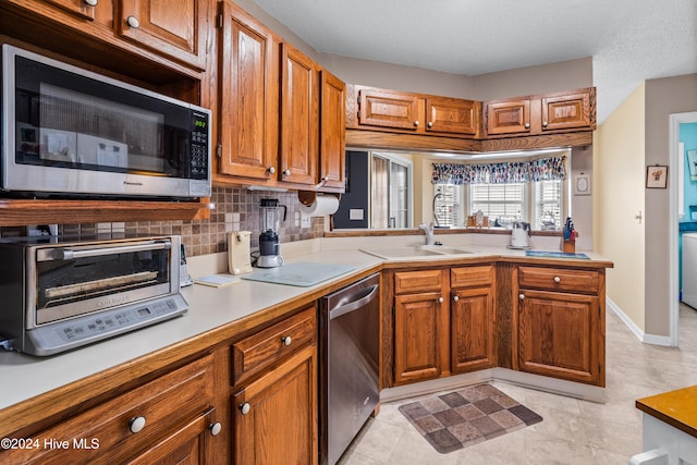 kitchen featuring a textured ceiling, sink, tasteful backsplash, light tile patterned floors, and appliances with stainless steel finishes