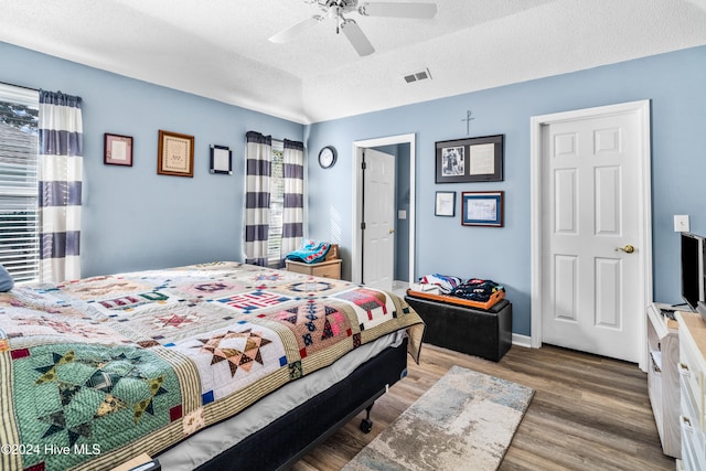 bedroom featuring hardwood / wood-style floors, ceiling fan, multiple windows, and a textured ceiling