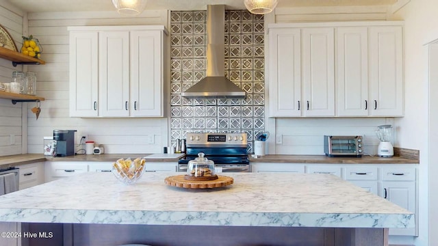 kitchen with a kitchen island, electric stove, wall chimney exhaust hood, and white cabinets