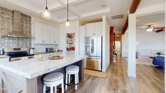 kitchen with stainless steel appliances, white cabinetry, wall chimney range hood, backsplash, and light hardwood / wood-style floors