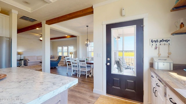 doorway featuring light wood-type flooring, ceiling fan with notable chandelier, and beam ceiling