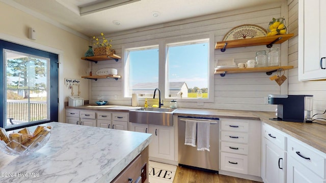 kitchen featuring dishwasher, wood walls, white cabinetry, and light hardwood / wood-style flooring