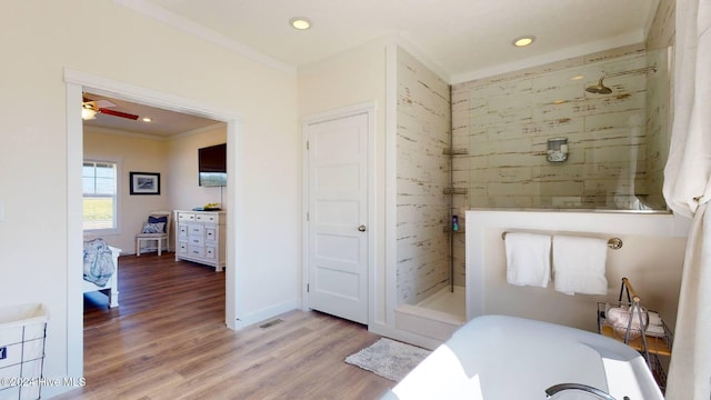 bathroom with crown molding, hardwood / wood-style flooring, a tile shower, and ceiling fan