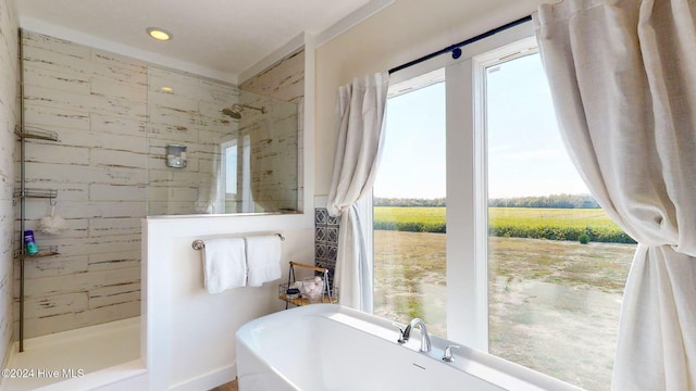 bathroom with a rural view, a healthy amount of sunlight, and plus walk in shower