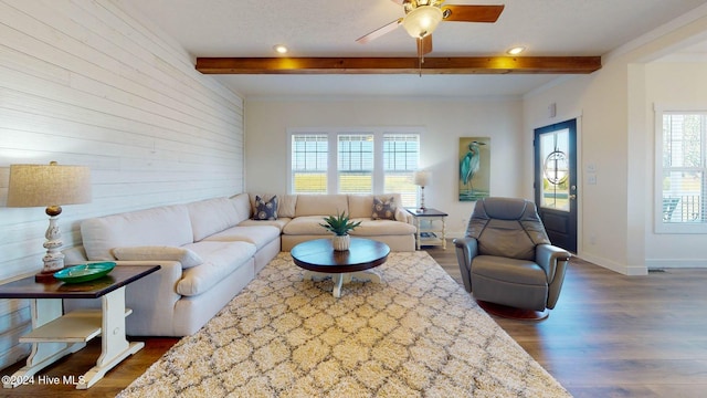 living room featuring dark wood-type flooring, beamed ceiling, and ceiling fan