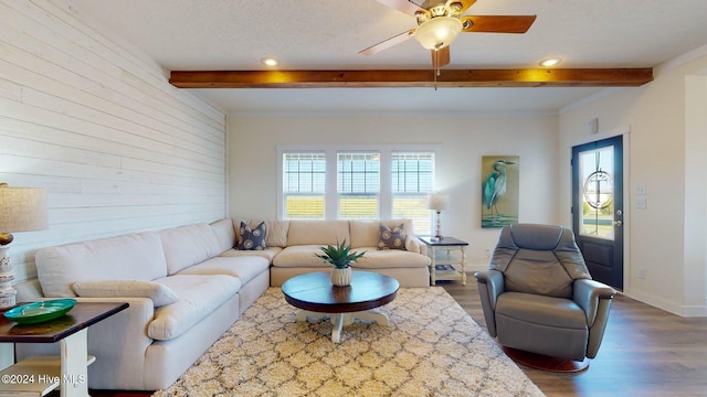 living room with a textured ceiling, beamed ceiling, dark hardwood / wood-style floors, and ceiling fan