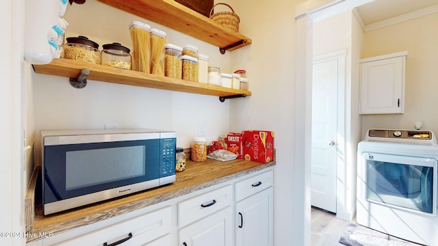 kitchen with washer / dryer, white cabinetry, light wood-type flooring, and crown molding