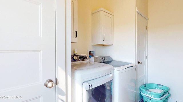 clothes washing area with cabinets and washer and clothes dryer