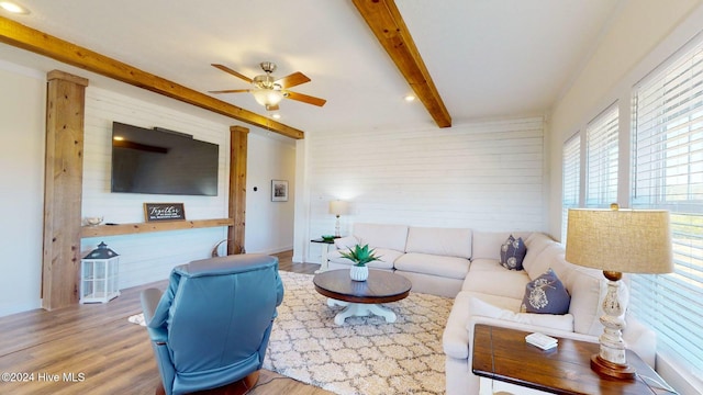 living room featuring beamed ceiling, light hardwood / wood-style floors, and ceiling fan