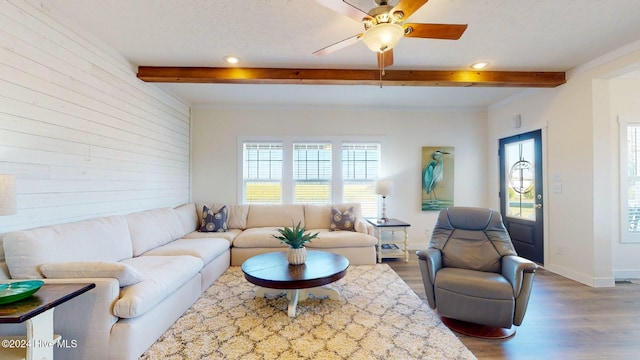 living room featuring a textured ceiling, hardwood / wood-style flooring, ceiling fan, and beam ceiling