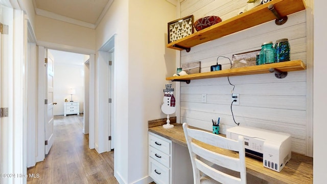 interior space with built in desk, light wood-type flooring, and crown molding