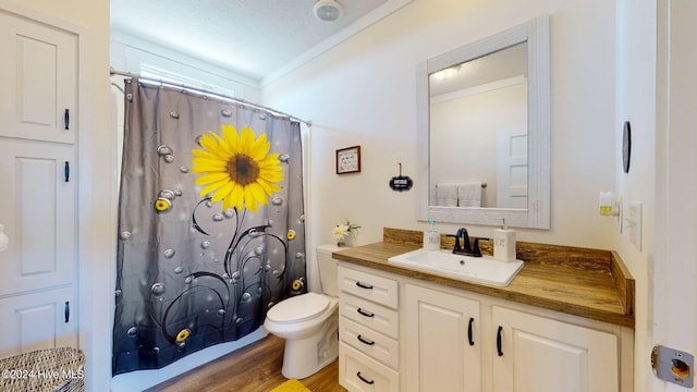 bathroom featuring ornamental molding, a textured ceiling, wood-type flooring, vanity, and toilet