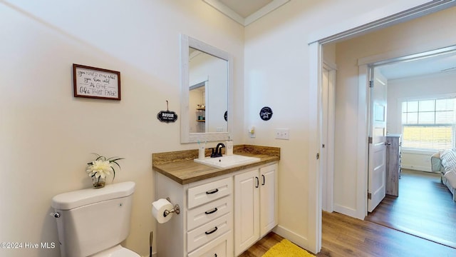 bathroom featuring wood-type flooring, vanity, toilet, and ornamental molding