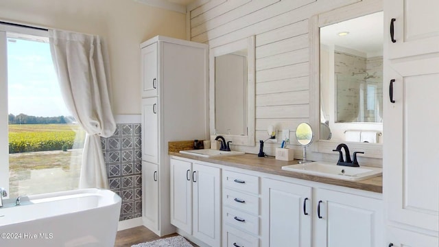 bathroom featuring hardwood / wood-style floors, wood walls, plus walk in shower, and vanity