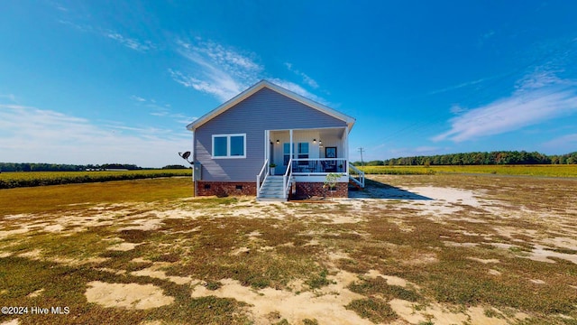 view of front of home featuring a porch, a front yard, and a rural view