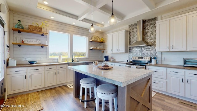 kitchen featuring white cabinetry, wall chimney range hood, hanging light fixtures, and stainless steel range with electric stovetop