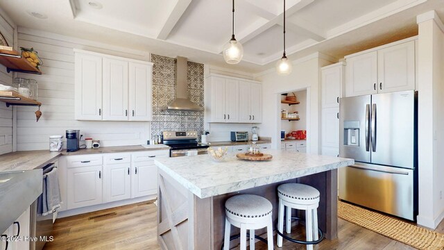 kitchen featuring white cabinetry, appliances with stainless steel finishes, light hardwood / wood-style floors, wall chimney exhaust hood, and a center island