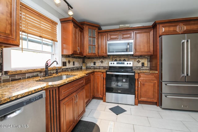 kitchen featuring decorative backsplash, sink, stainless steel appliances, and light stone counters