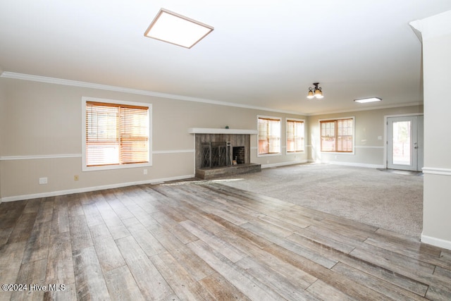 unfurnished living room featuring hardwood / wood-style floors, plenty of natural light, crown molding, and a brick fireplace