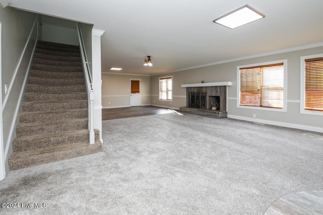 unfurnished living room featuring carpet flooring, crown molding, and a brick fireplace