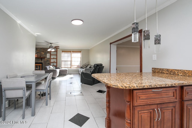 kitchen with a stone fireplace, ceiling fan, light tile patterned floors, and ornamental molding