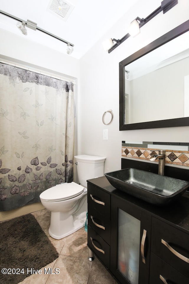 bathroom featuring tile patterned floors, vanity, toilet, and backsplash