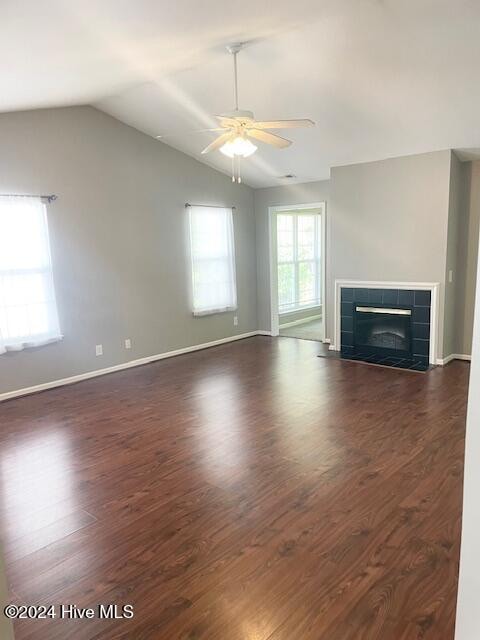 unfurnished living room with ceiling fan, vaulted ceiling, dark hardwood / wood-style floors, and a fireplace